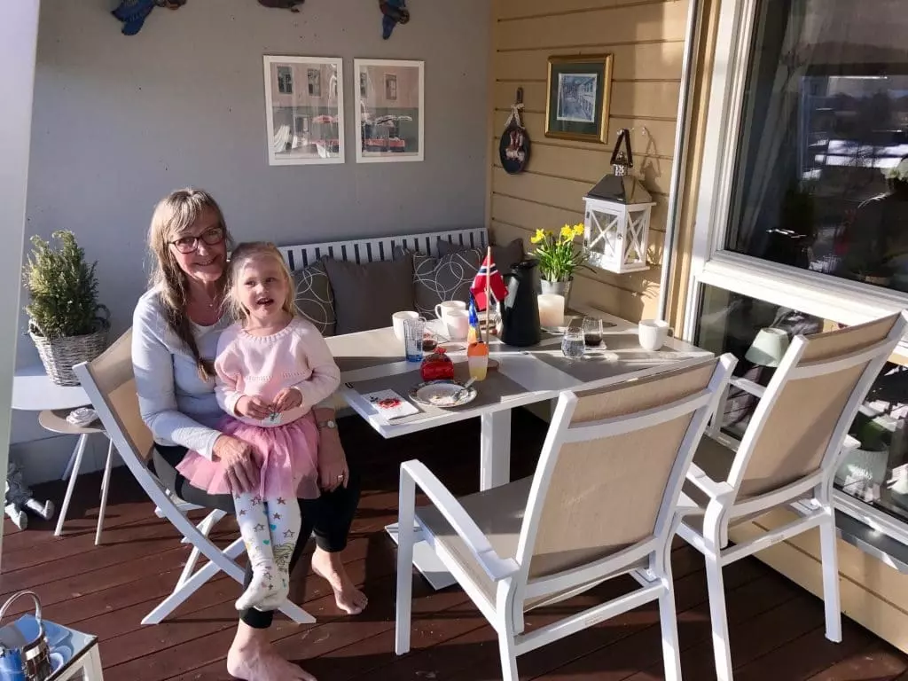 Fine Design spisegruppe på en liten terrasse. I en stol sitter en eldre dame med en liten jente på fanget
