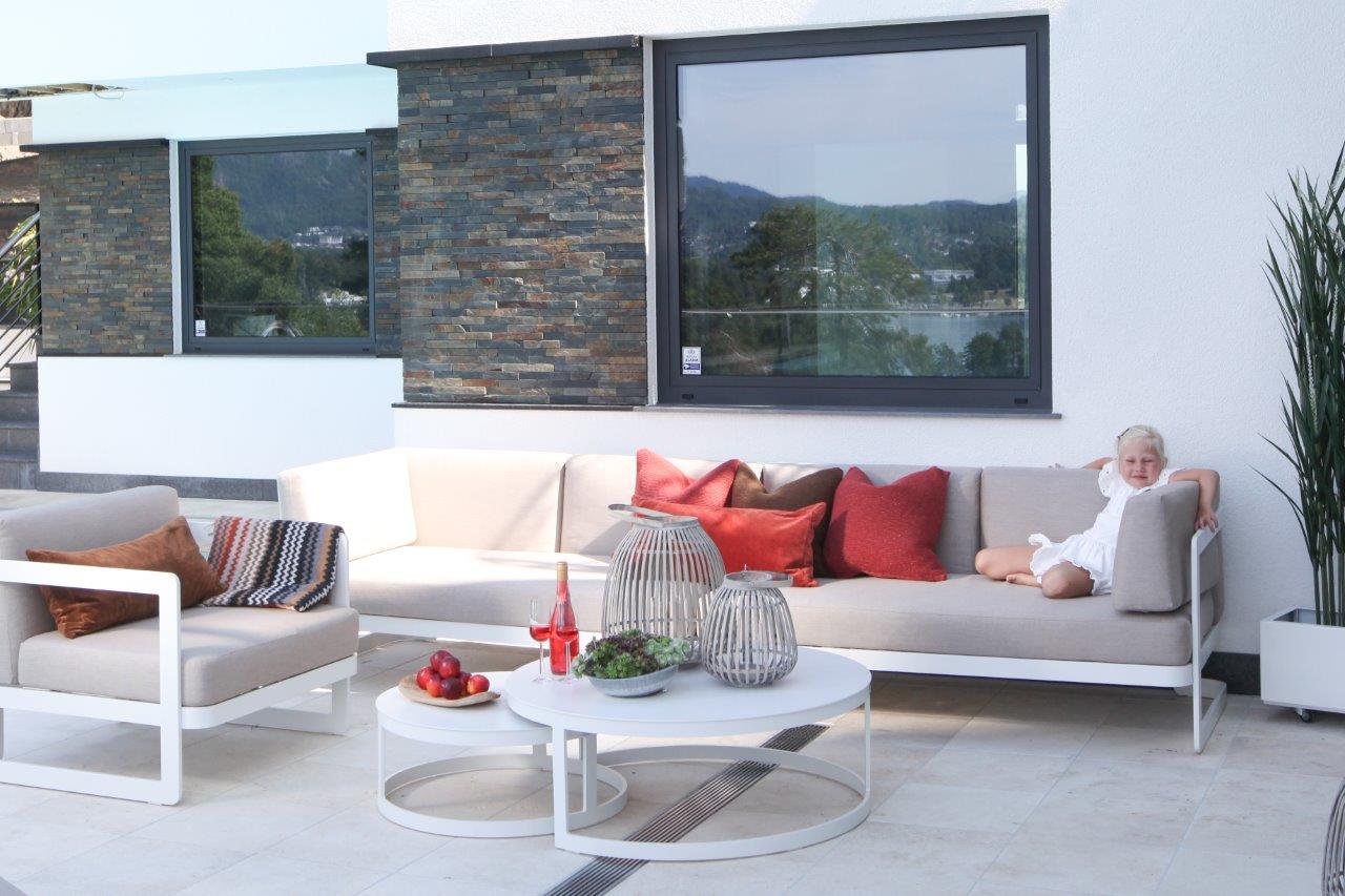Hagemøbler og utemøbler fra Fine Design. Stor, lys hagesofa med lik stol. Liten jente sitter i sofaen.