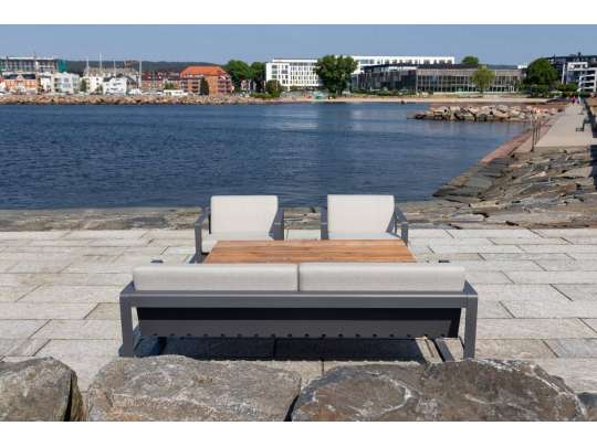 Sundays Core sofagruppe i mørkgrå aluminium med puter i lys grå farge på uteplass ved havet