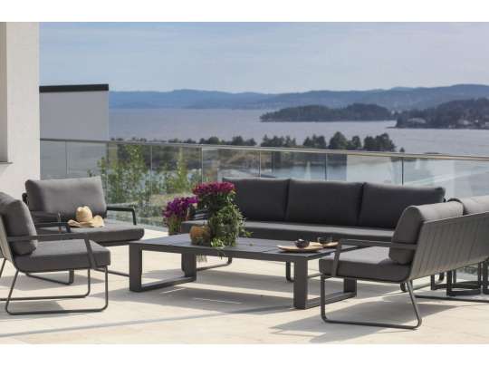 Sofagruppe - 3-seter og tre hagestoler i sort aluminium med grå puter sammen med et hagebord på veranda