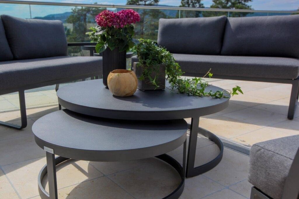 Runde, sorte balkongbord som kan dyttes under hverandre - mellom Fine Design Hagemøblers hagesofaer på terrrasse