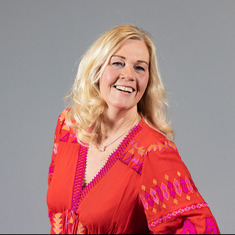 En smilende Marianne Aanerod i Fine Design Hagemobler i rød topp