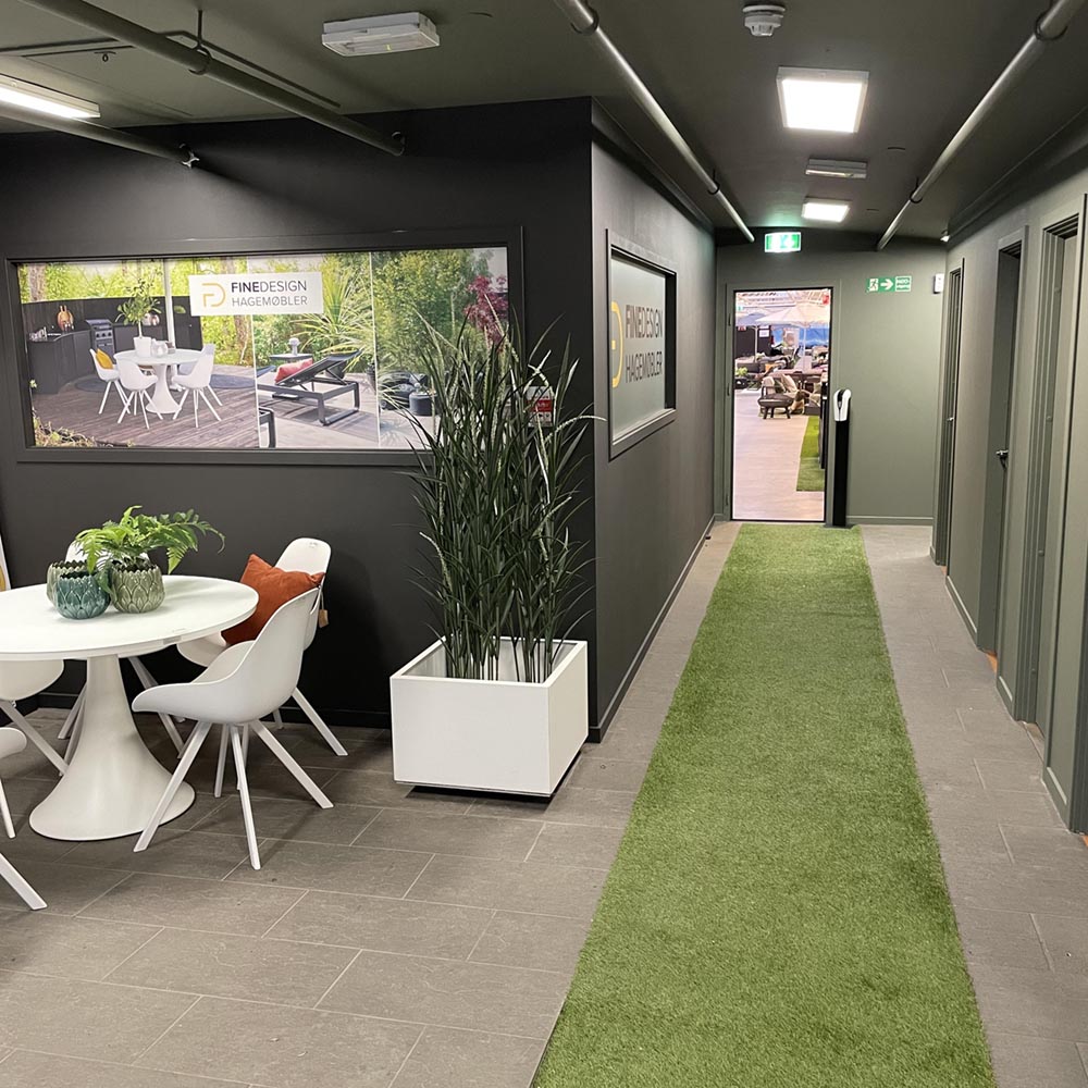 Inngangspartiet til Fine Design utemøbler, med hvitt utebord og hvit blomsterkasse