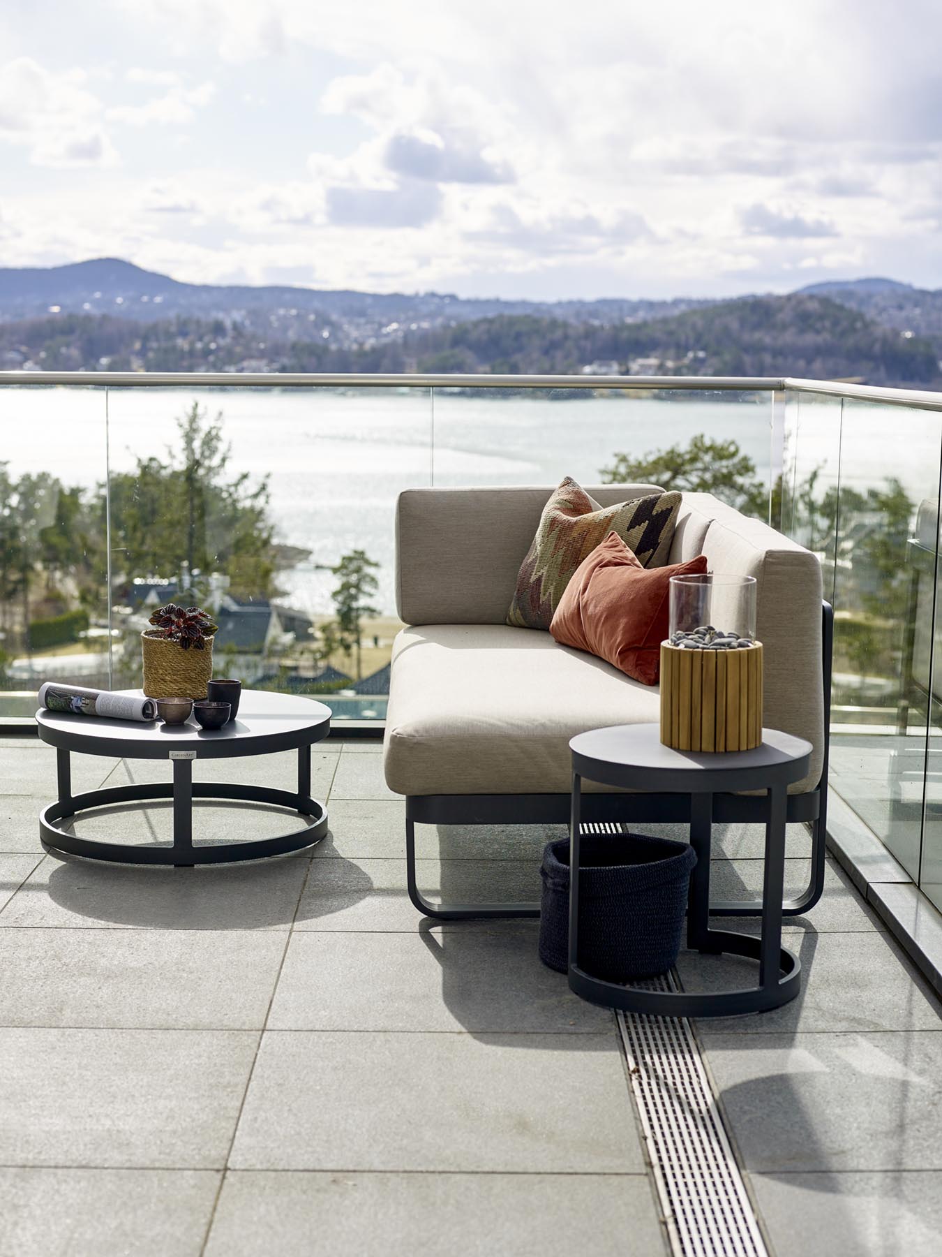 Liten modulsofa med rundt bord i sola på flott terrasse med fantastisk utsikt