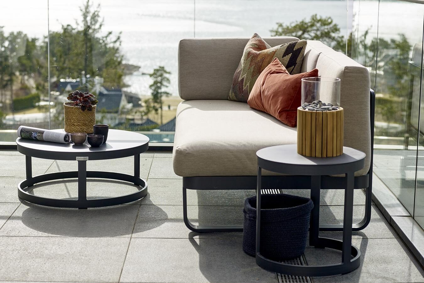 Liten modulsofa med rundt bord i sola på flott terrasse med fantastisk utsikt