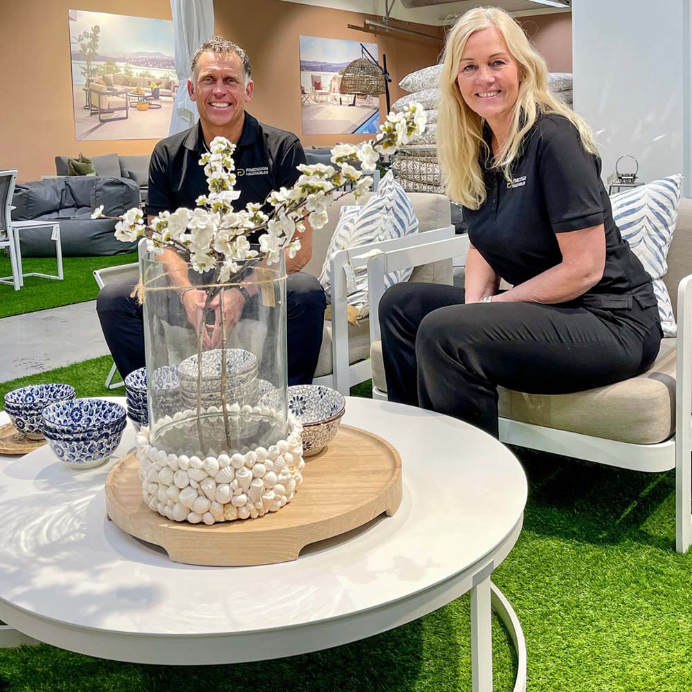Kjetil og Marianne i Fine Design Løxaveien 5 sittende i beige og hvit hagesofa bak hvitt rundt utebord