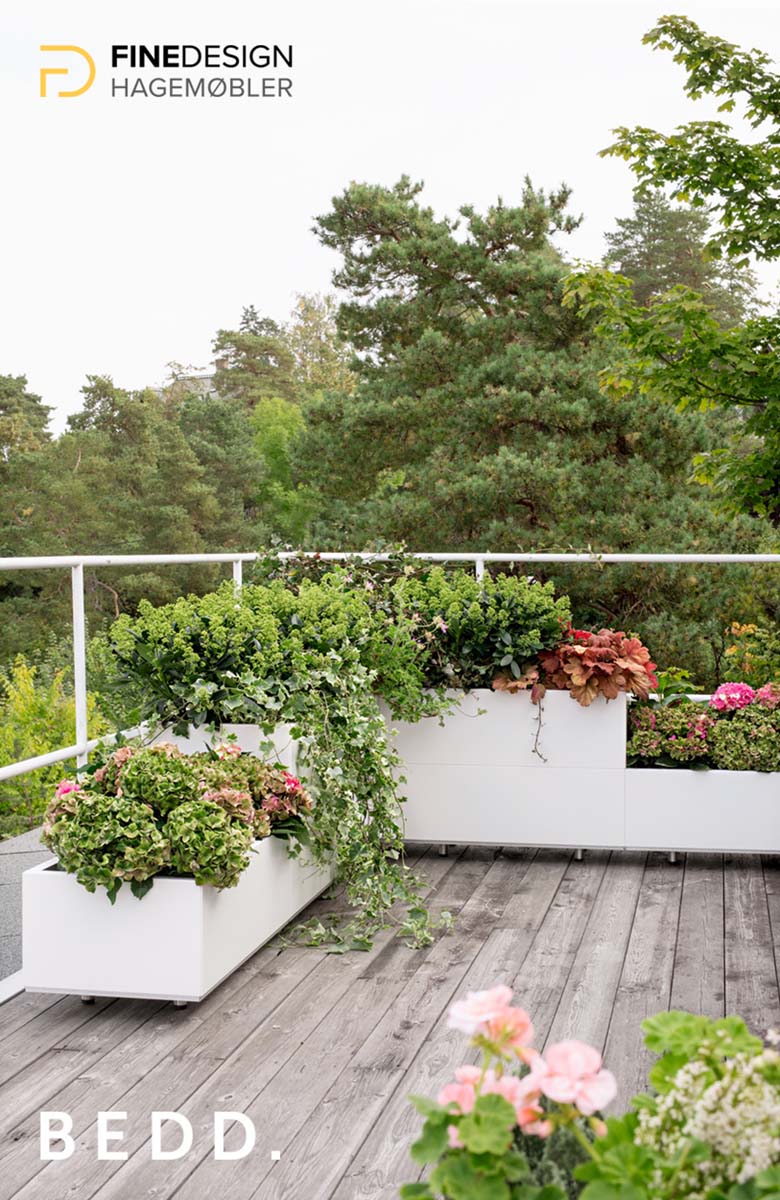 Beplantede hvite BEDD blomsterkasser i vinkel og i ulik høyde på veranda