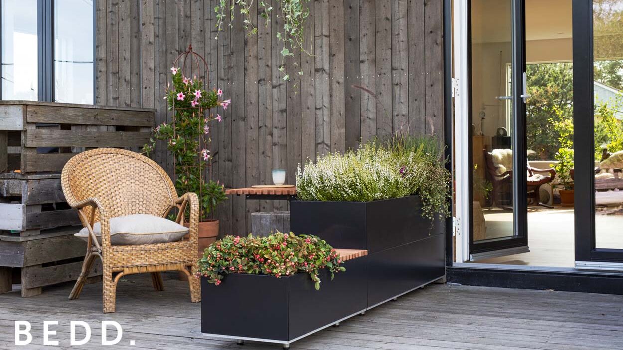 Sort BEDD plantekasse i to høyder med bord på uteplass